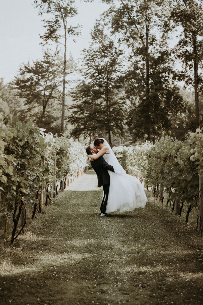 Rebecca and Max, the bride and groom hold onto each other in the middle of the vineyard, during their first look photos.