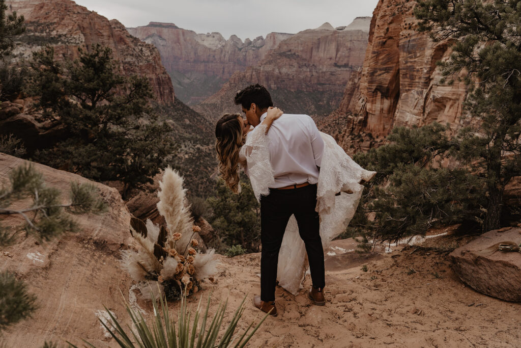 Groom dips bride during their destination elopement surrounded by rocky mountains and terrain.