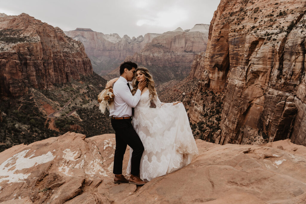 Groom embraces bride during their destination elopement surrounded by rocky mountains and terrain.