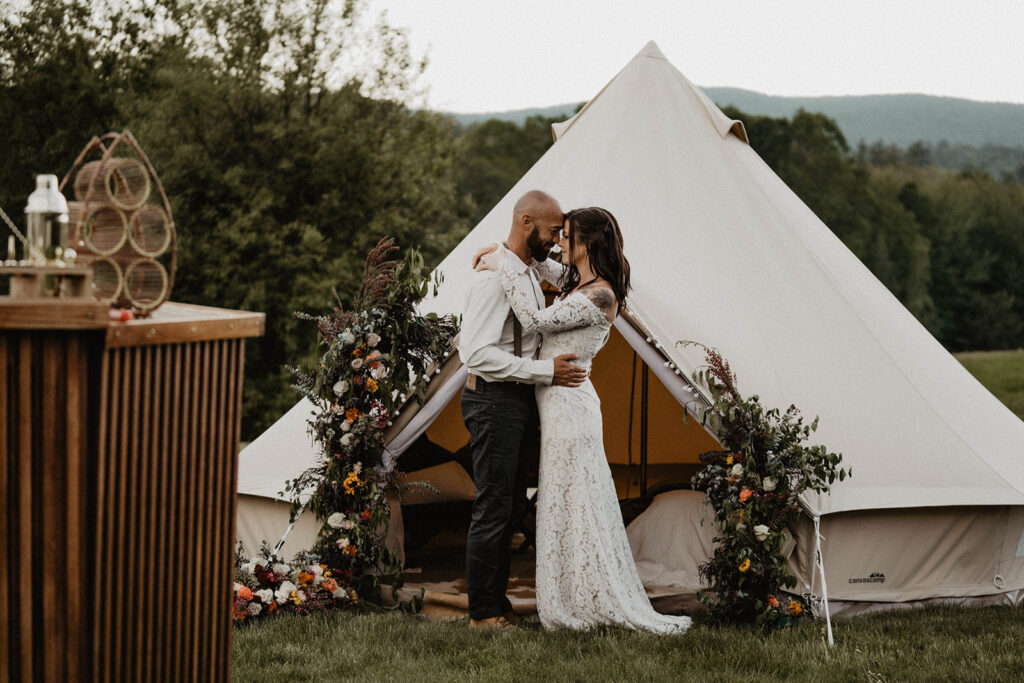 Bride and groom kiss in front of luxury tent during their destination elopement.
