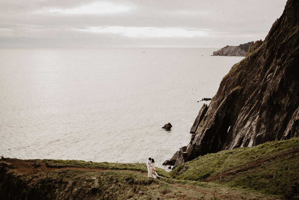 Bride and groom walk grassy cliffs during their destination elopement. 