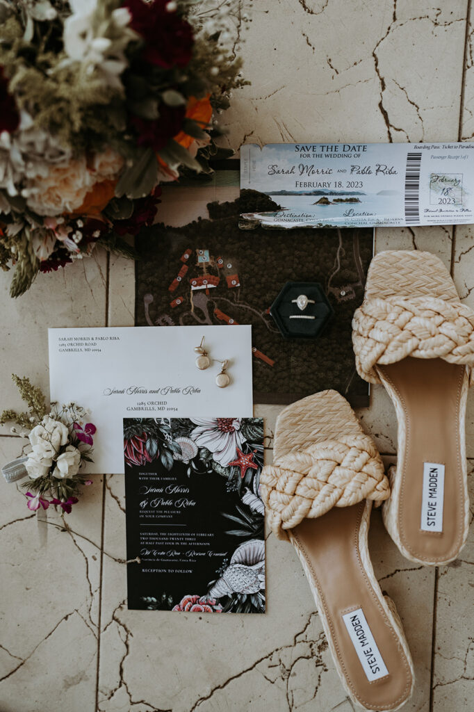 Flat layout of save the date, invitations and map with flowers, jewelry and the bride's shoes during their destination wedding in Costa Rica. 