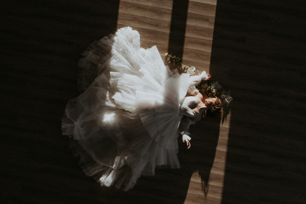 Drone shot of a bride laying on the ground in a madeleines daughter dress at the Greenery in Milton New Hampshire